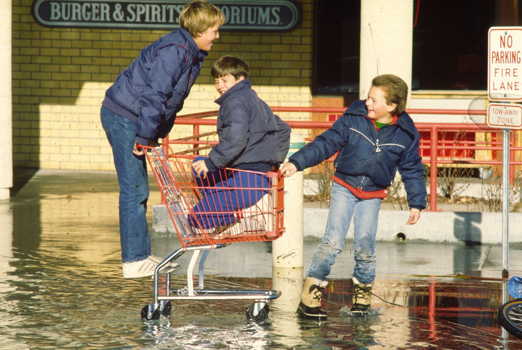 Boys play in flooded West Park Plaza parking lot, 1986